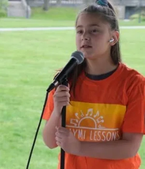 A young singer performing with a microphone at an outdoor event