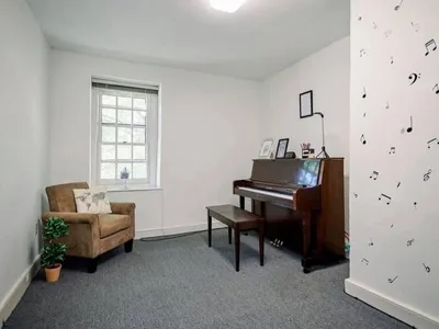 A lesson room at Downingtown Music Academy with an upright piano, bench and armchair