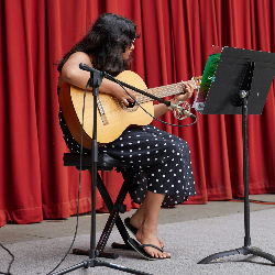 Image of a student playing the guitar at a recital