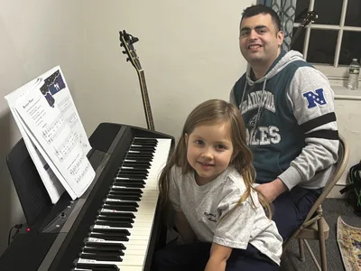 Piano teacher Kevin Guttilla with a young student at the keyboard during a lesson